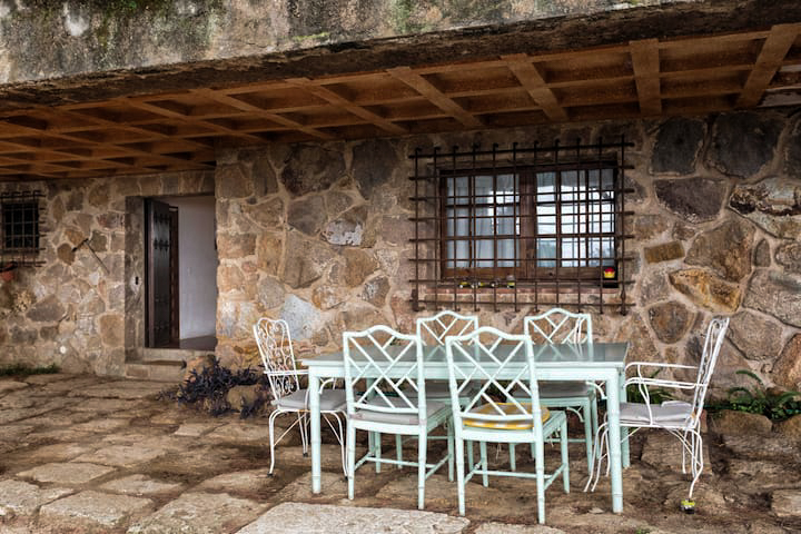 The covered stone terrace with table and chairs