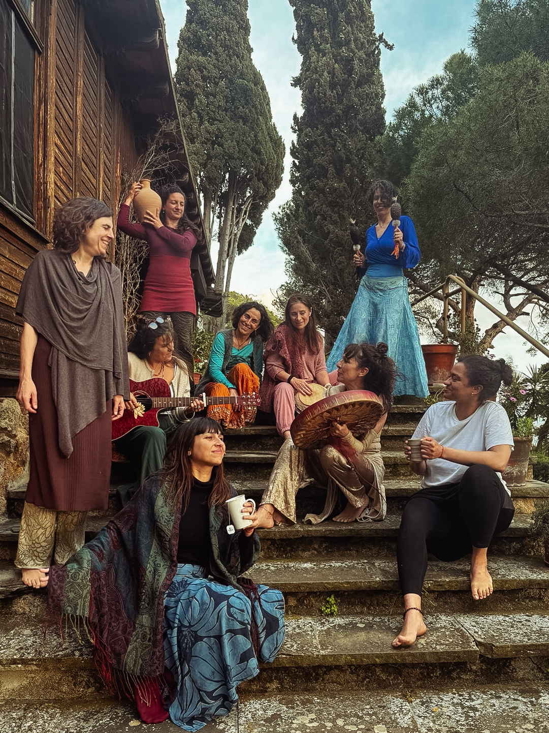A circle of women gathered on stone steps outside the wooden house