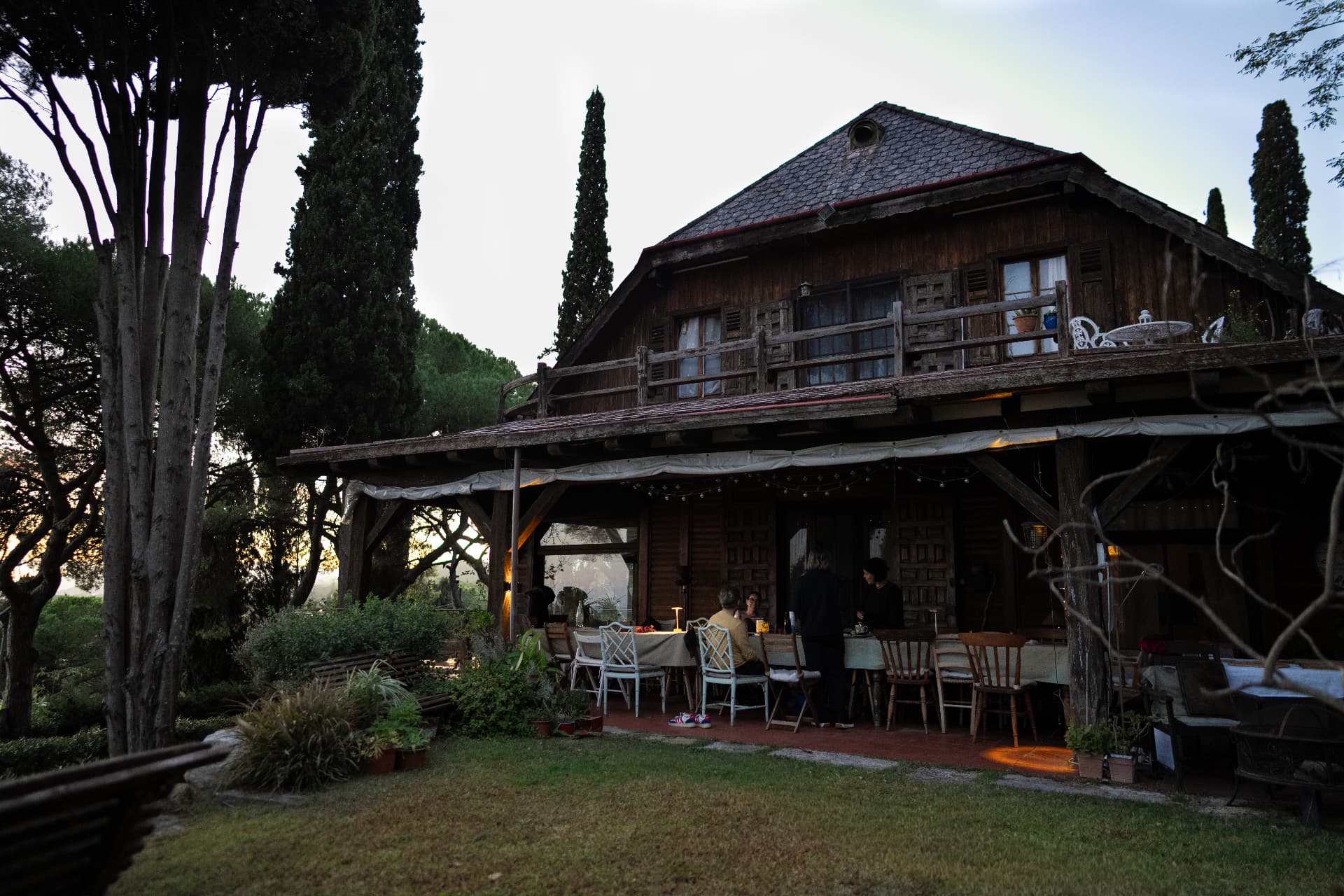 The wooden house at dusk with a long table set under the porch