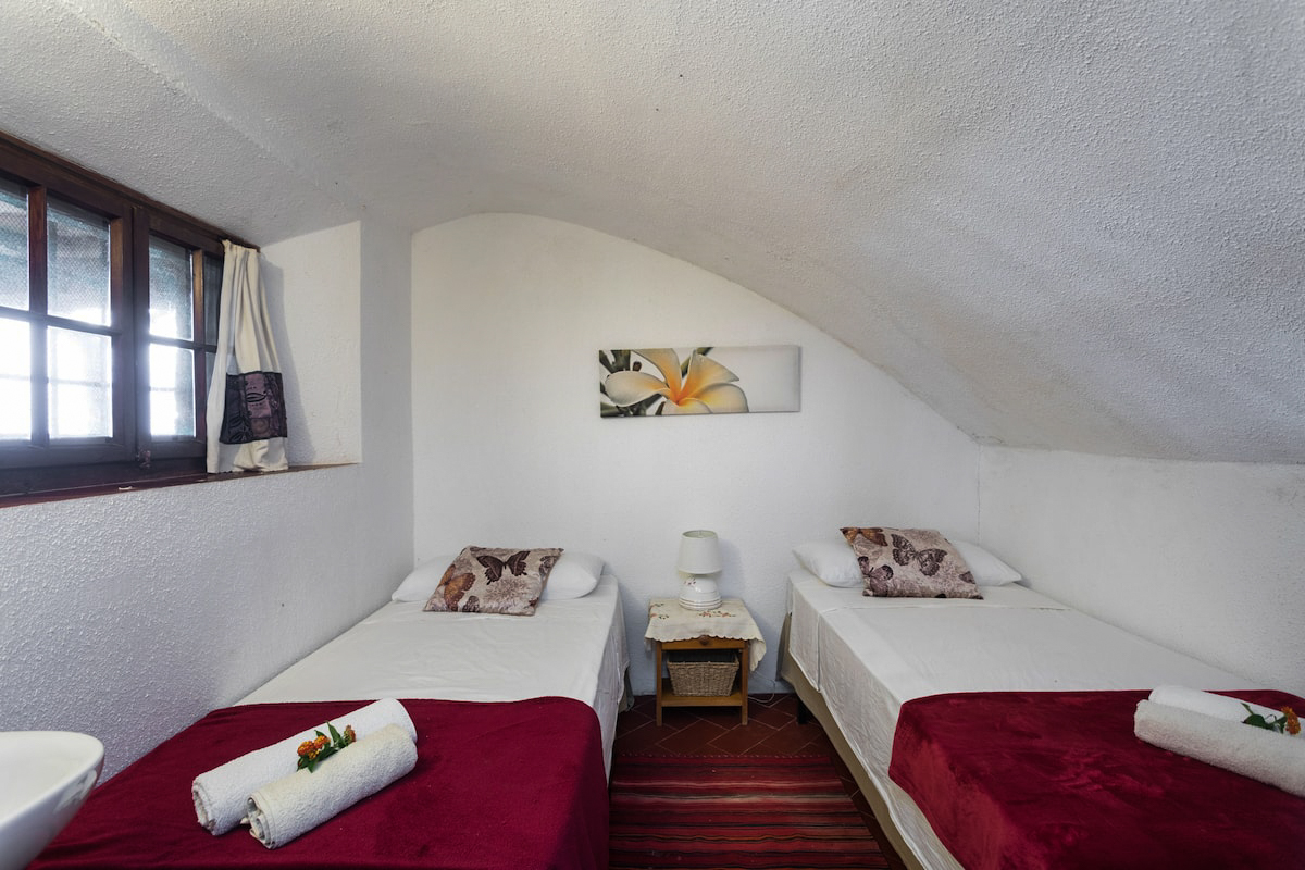 The smaller bedroom with two single beds under a vaulted ceiling