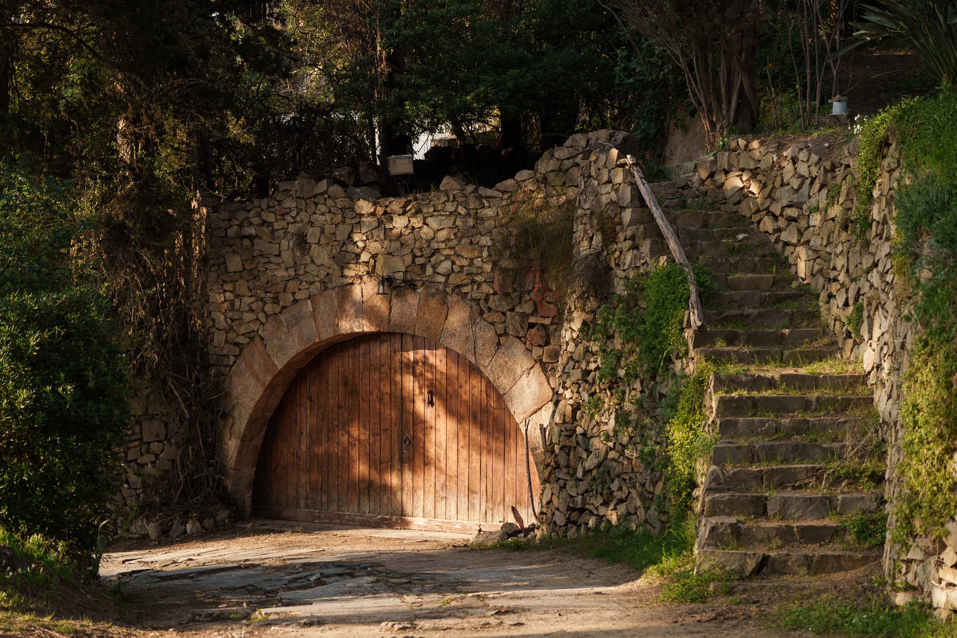 A stone archway with a wooden door and steps climbing the hillside